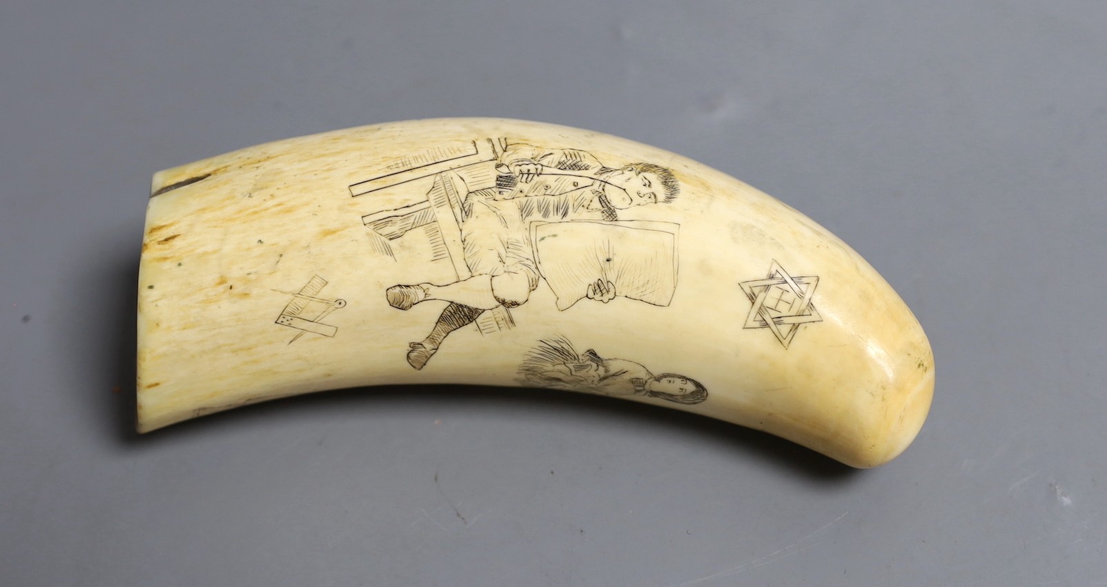 A 19th century scrimshaw sperm whale tooth, inscribed CONCORDIA, decorated with a seated gentleman reading a newspaper, Masonic symbols, and three ladies, 14cm